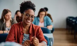 Happy African American woman attending a lecture in university classroom and looking at camera.